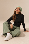 Elara women's black long-sleeve roll neck top, shown in a seated front view.